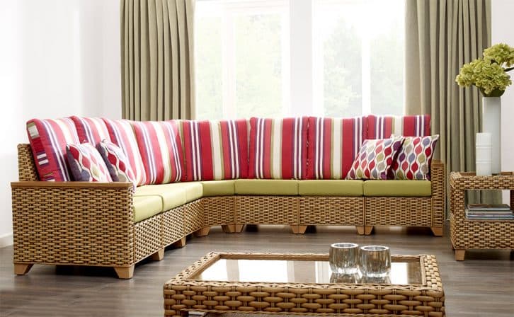 Striped red & white cushions on a L shaped piece of Cane furniture in a modern living room