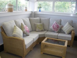 Cane furniture with grey pillows with a cane table