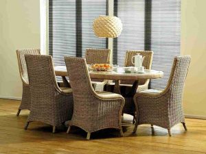 cane conservatory furniture dining table set in a modern room with windows behind